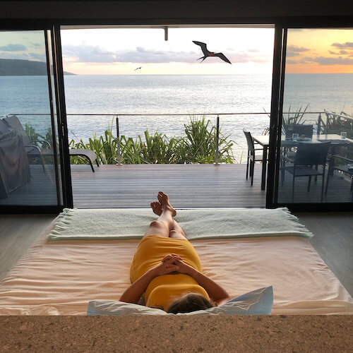Swell Lodge girl relaxing on king bed with ocean views