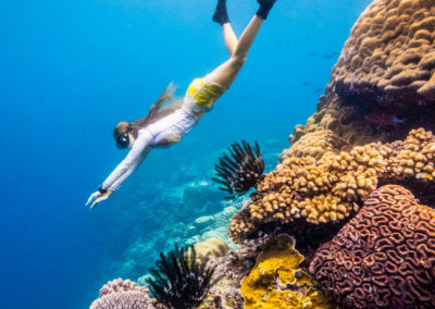 Woman free diving and snorkelling on Christmas Island with fish and coral reef with Swell Lodge